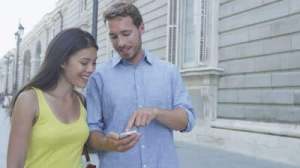 stock-footage-couple-using-mobile-cell-smart-phone-in-city-outdoors-man-showing-smartphone-screen-laughing-happy